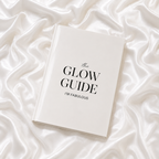 The Glow Guide by I’M FABULOUS, an elegant white hardcover skincare book displayed on luminous white silk.