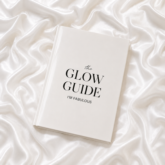 The Glow Guide by I’M FABULOUS, an elegant white hardcover skincare book displayed on luminous white silk.